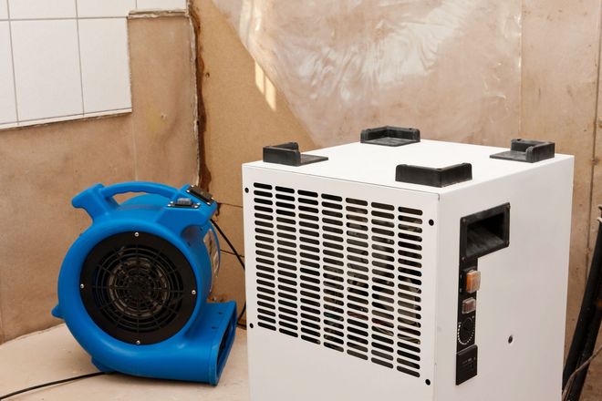 Blue and white portable industrial blower and air machine in a room against a wall