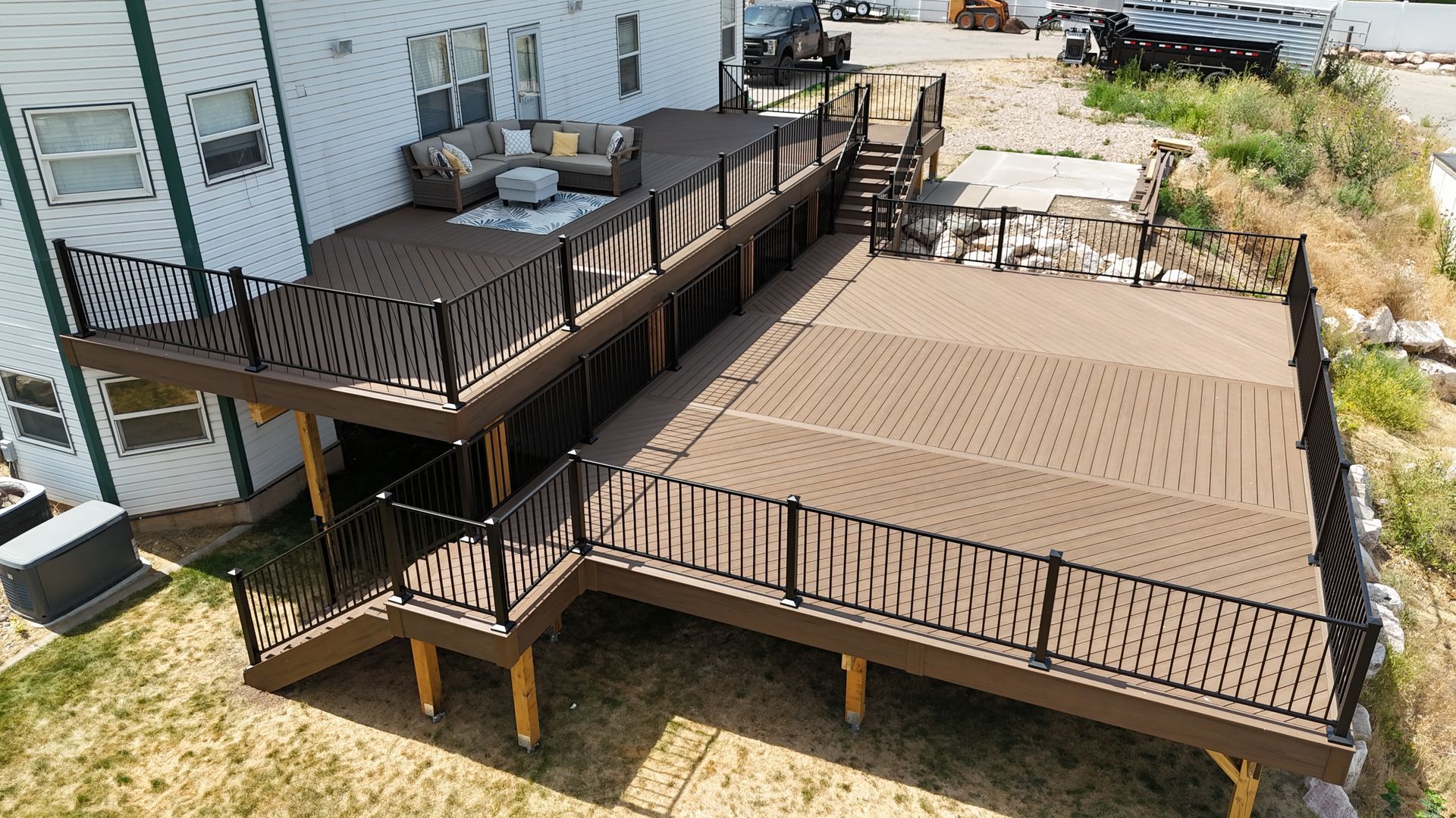 Two-level brown wooden deck attached to a house in a backyard yard