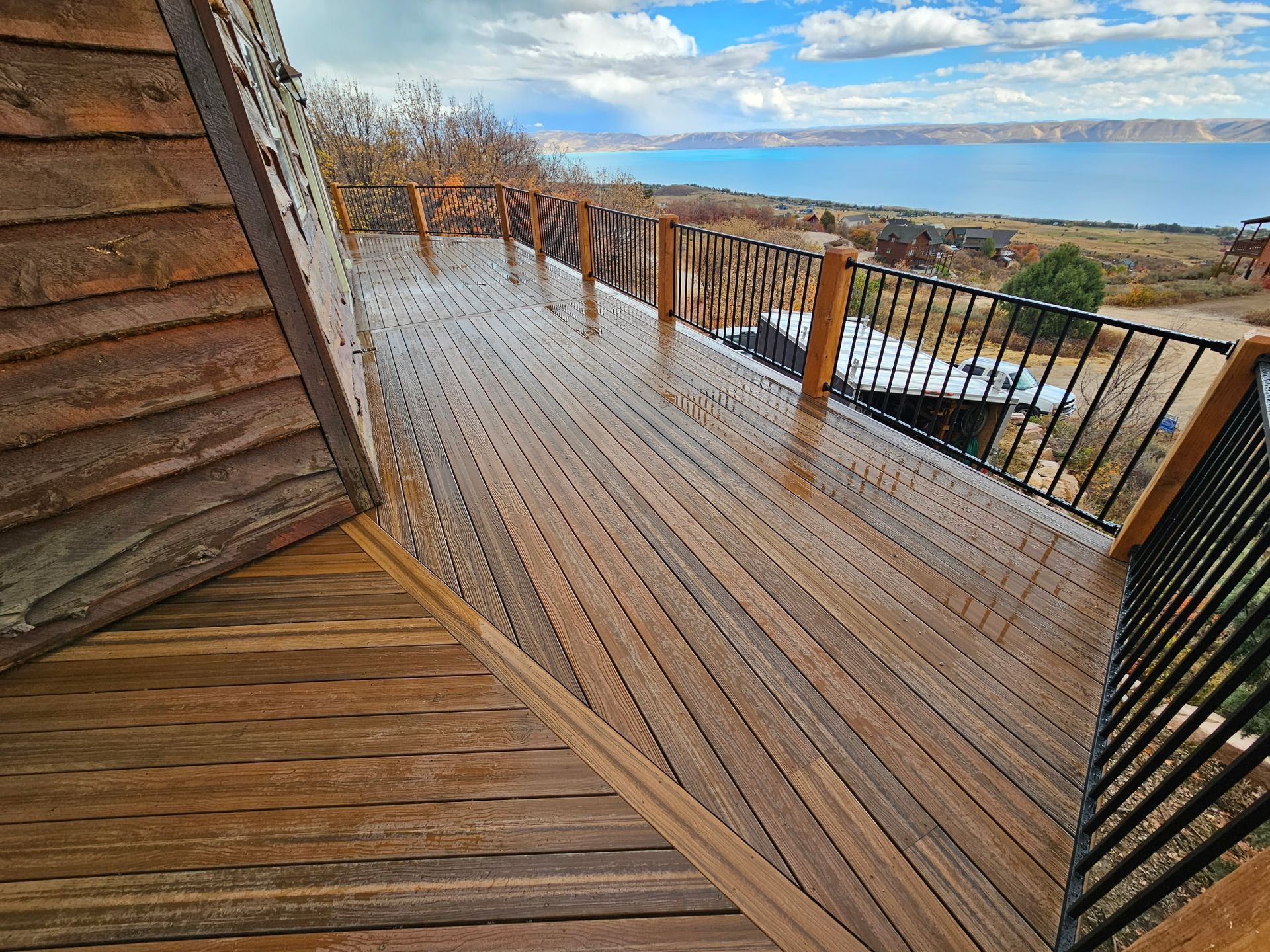 Wet wooden deck and balcony with railing overlooking a cloudy landscape