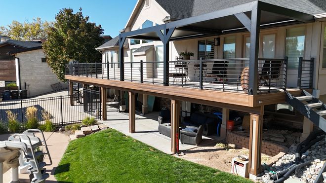 A modern rooftop deck featuring a dining set, a grill, and decorative plants under a translucent slatted roof.