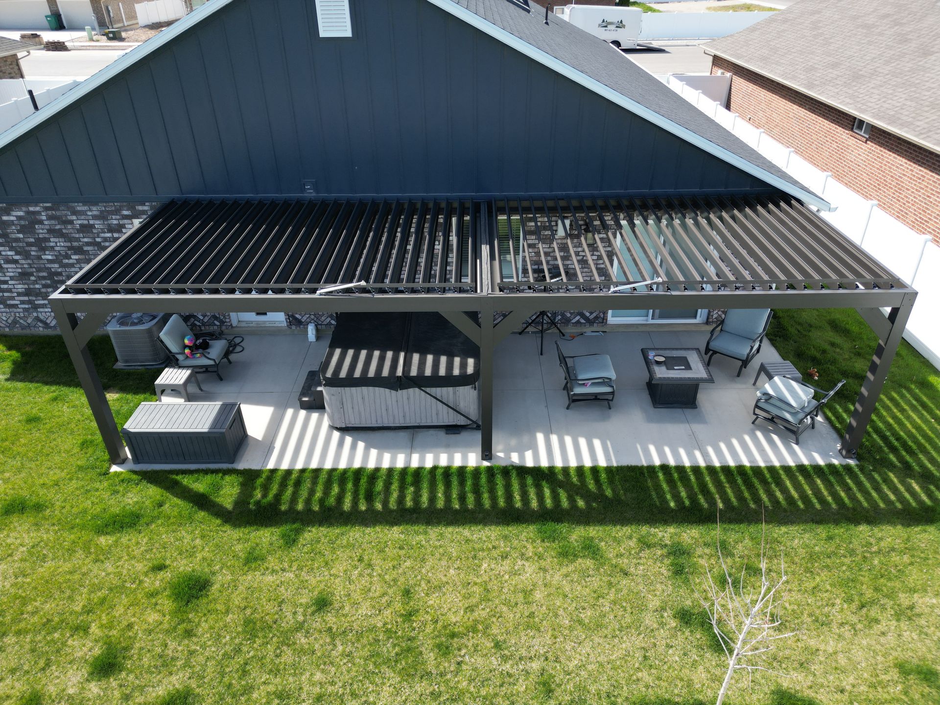 Covered patio with outdoor dining and lounge seating beside a house, overlooking a grassy yard