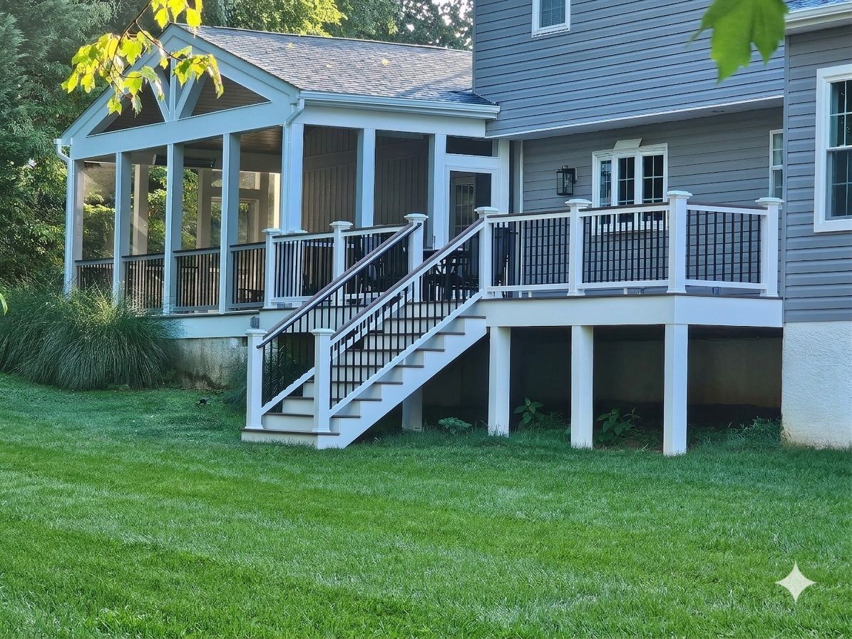 House with white-railed porch and stairs leading to a raised composite deck on a green lawn
