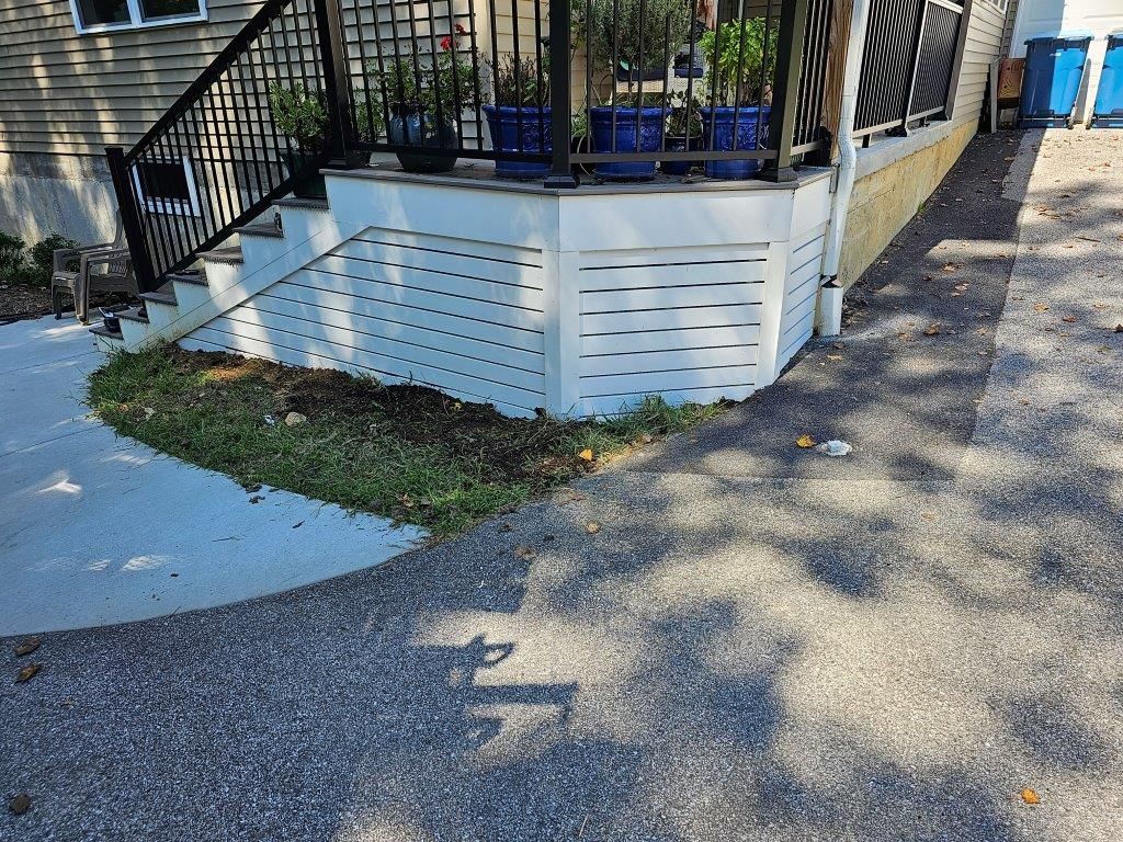A house with a porch and stairs next to a driveway.