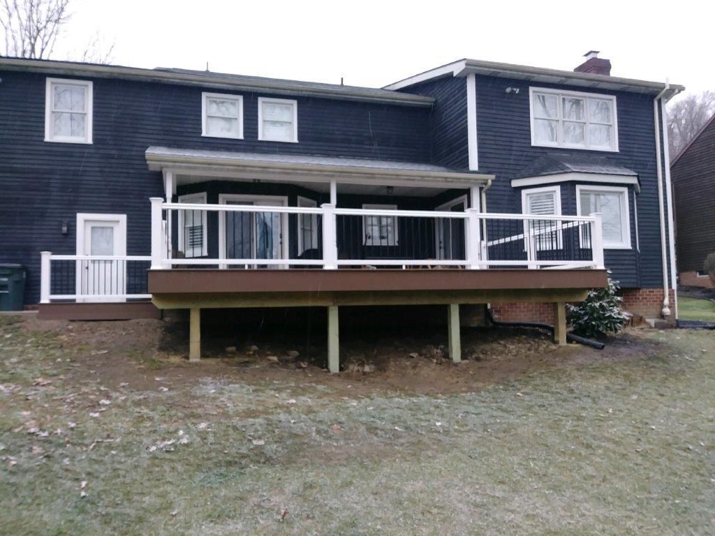A black house with a large deck in front of it.
