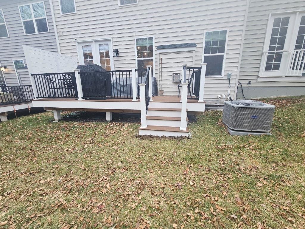 A backyard with a deck and stairs in front of a house.
