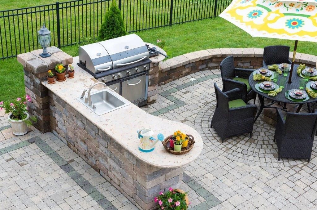A patio with a table and chairs and a grill.