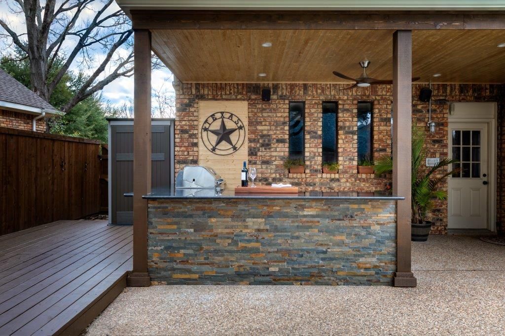 A patio with a brick wall and a stone counter top with a texas star on it.