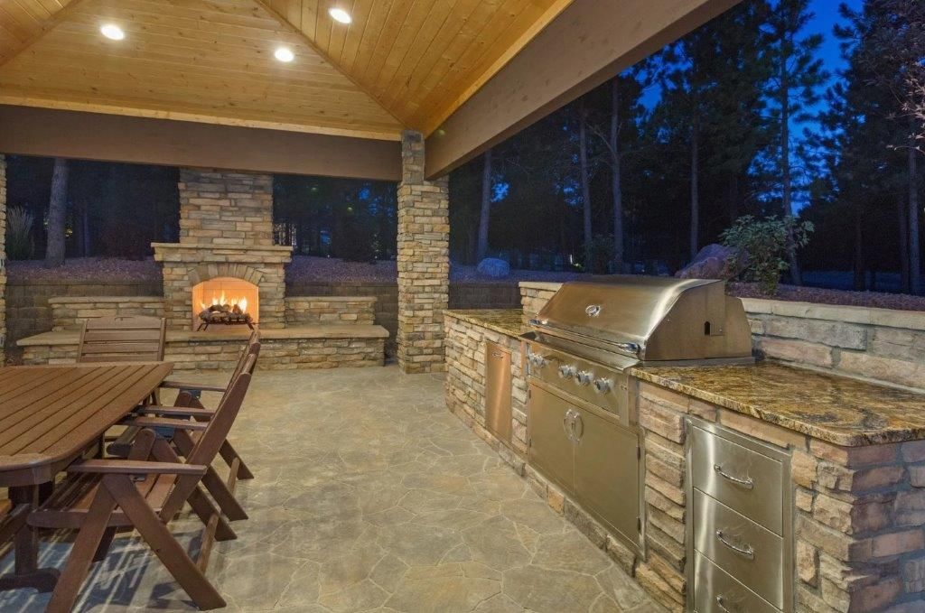 A large outdoor kitchen with a table and chairs and a fireplace.