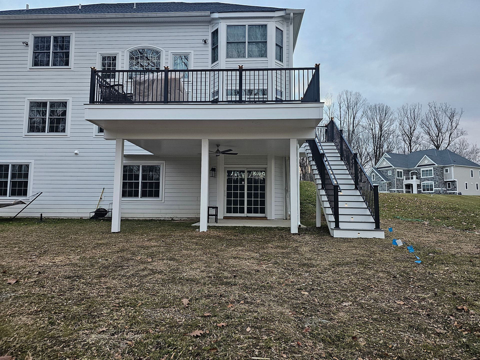 A large white house with a large deck and stairs leading up to it