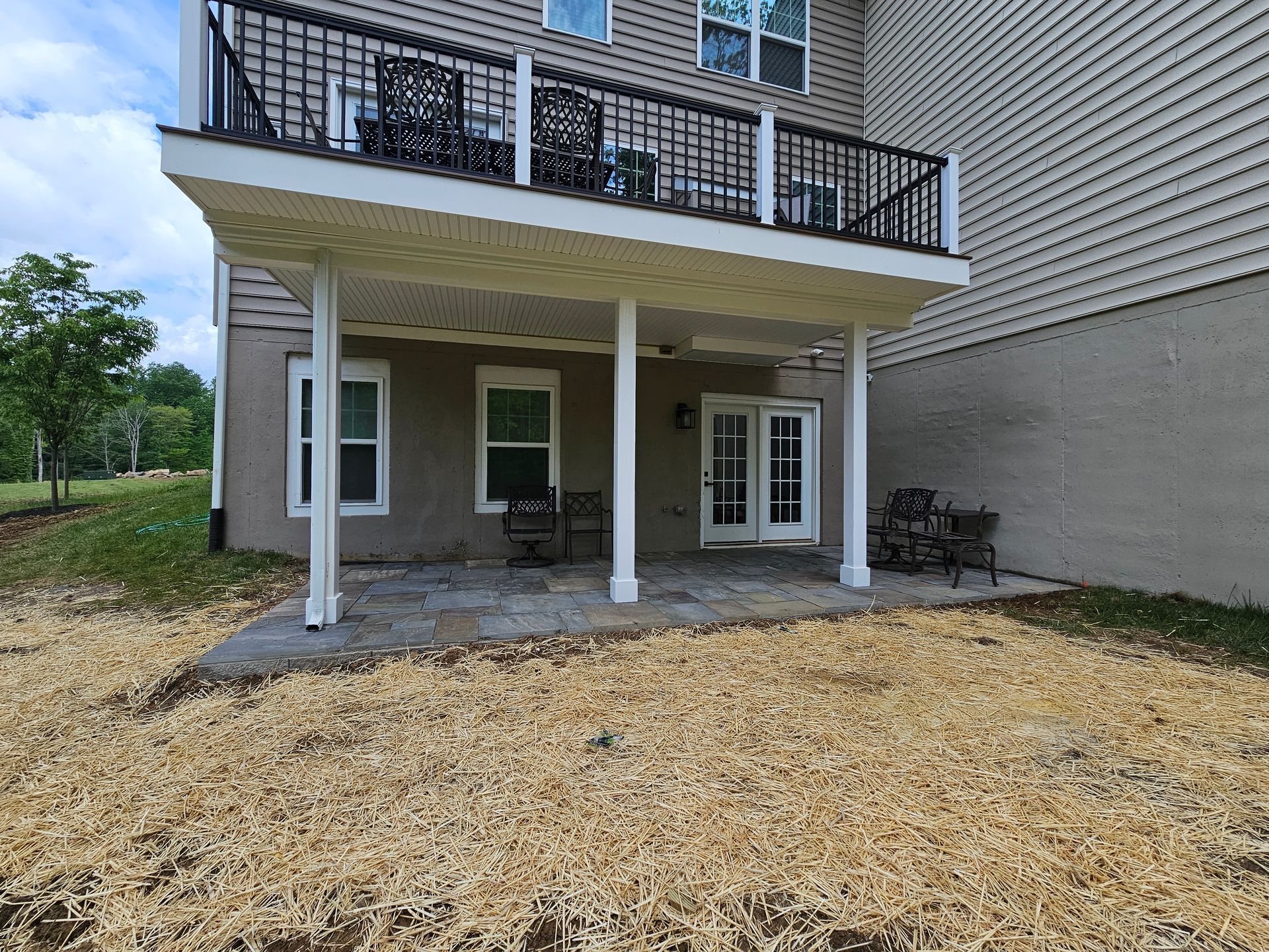 The backyard of a house with a large deck and patio