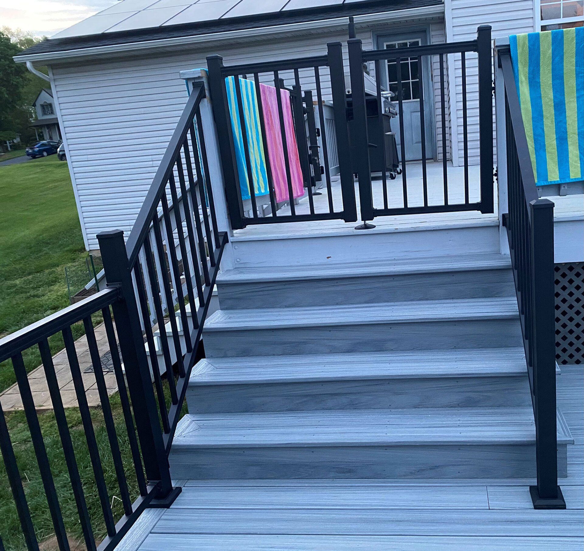 A deck with stairs and a black railing and towels hanging on the railing