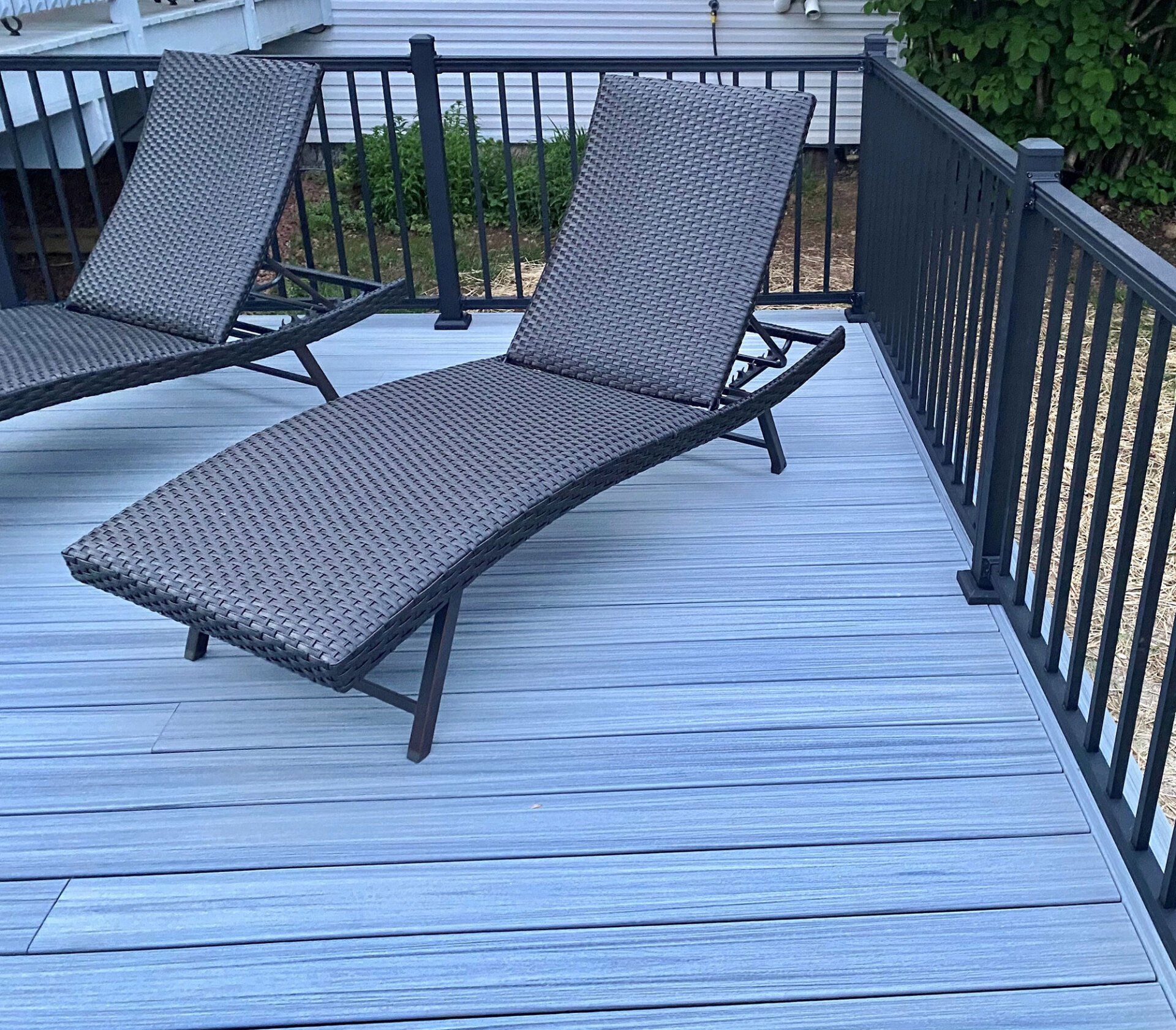 Two lounge chairs are sitting on a deck next to a railing