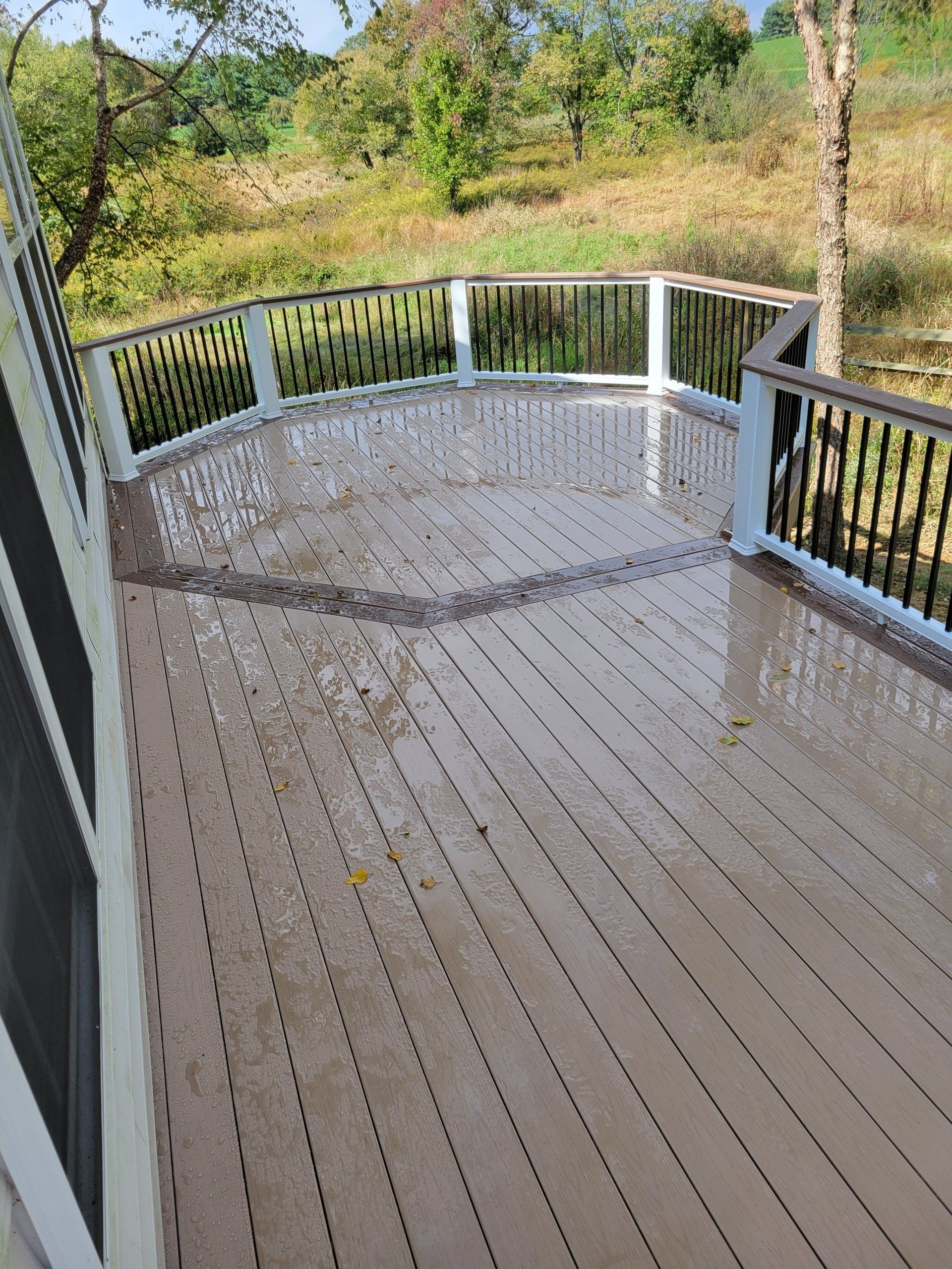 A large wooden deck with a railing and a view of a river
