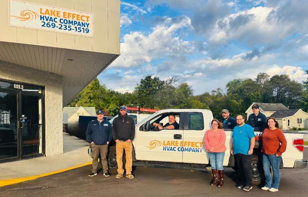 Group of people posing by a white truck with 
