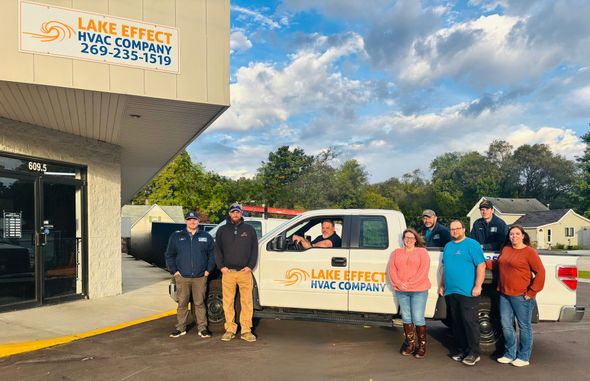 Group of people standing outside a building and a truck with a company logo 
