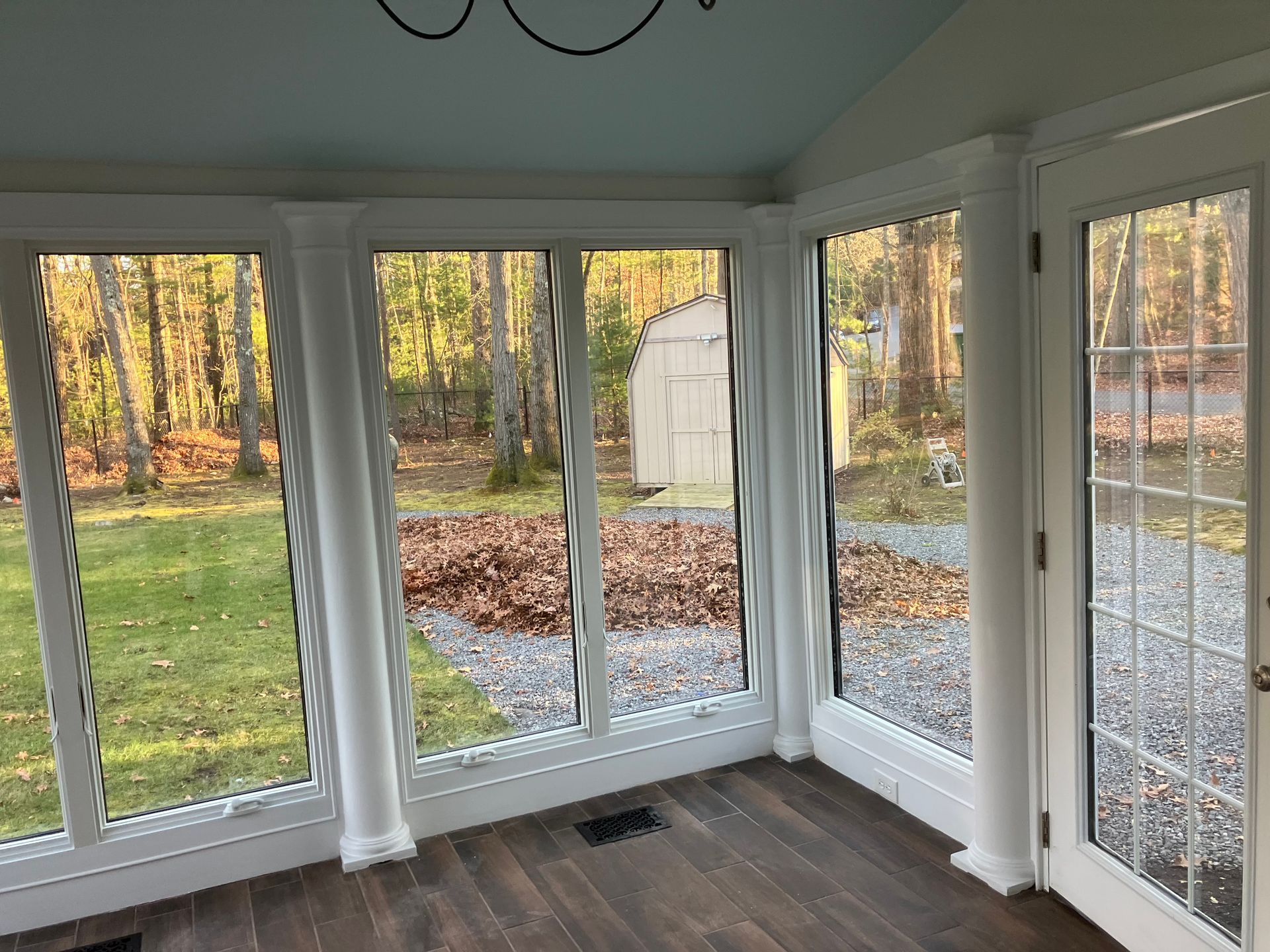 A sun room with a lot of windows and a wooden floor.