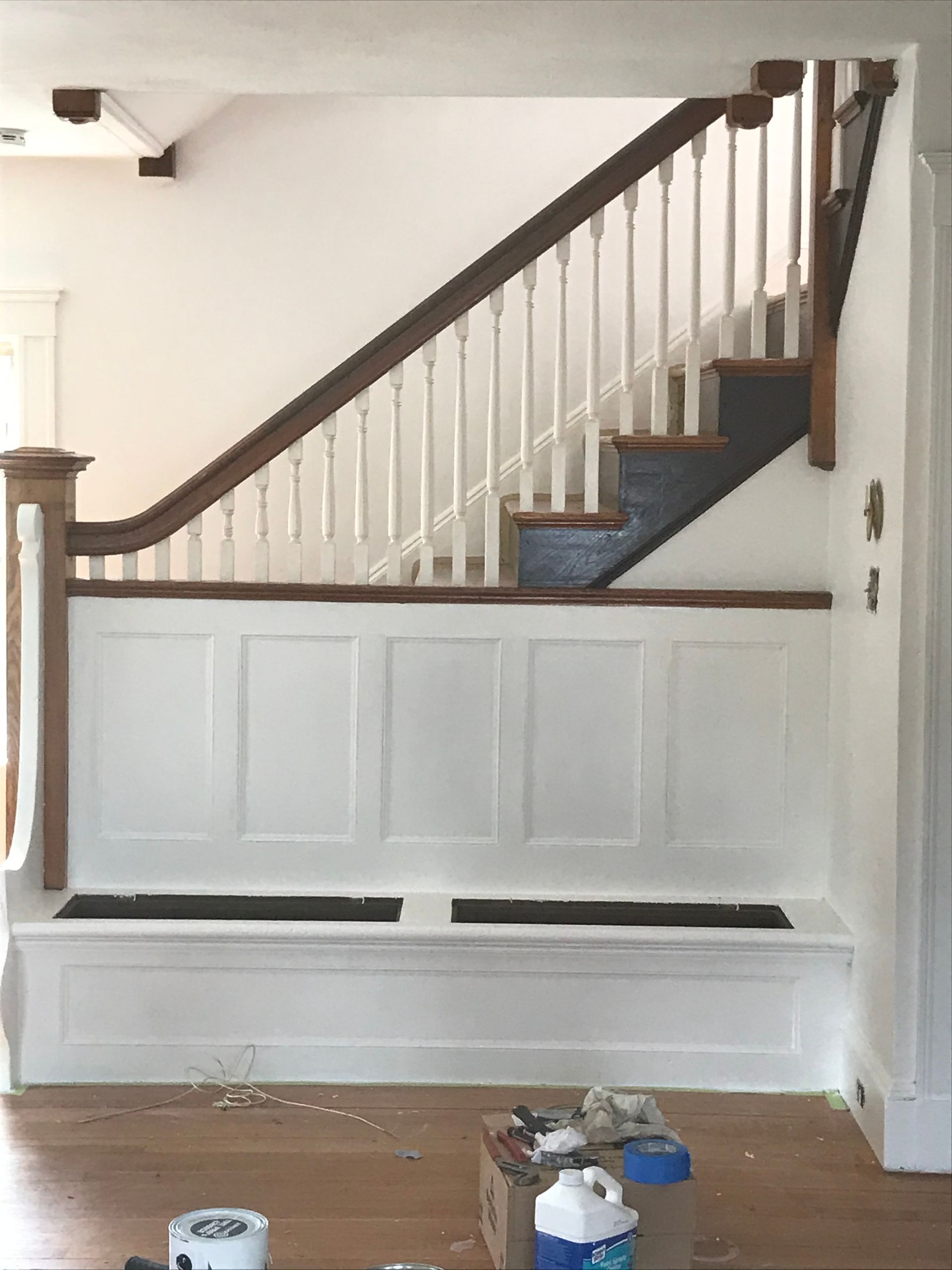 There is a bench under the stairs in the living room.