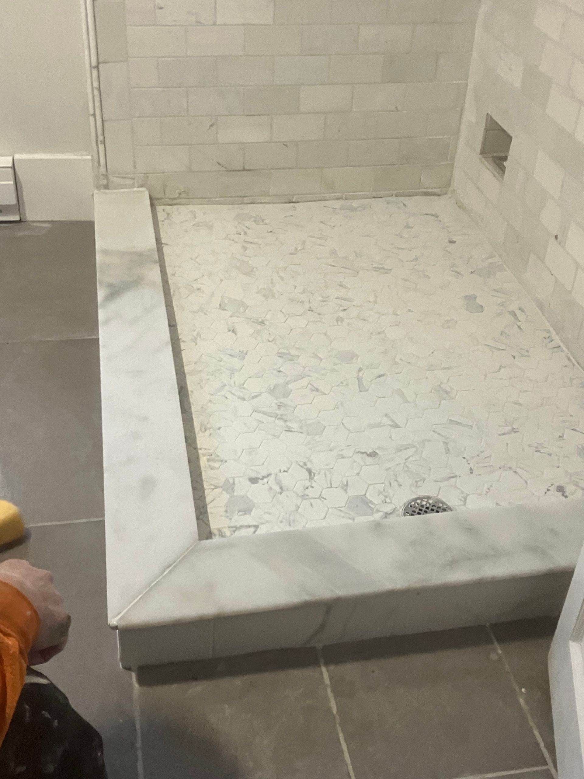 A person is standing in a bathroom next to a shower stall.