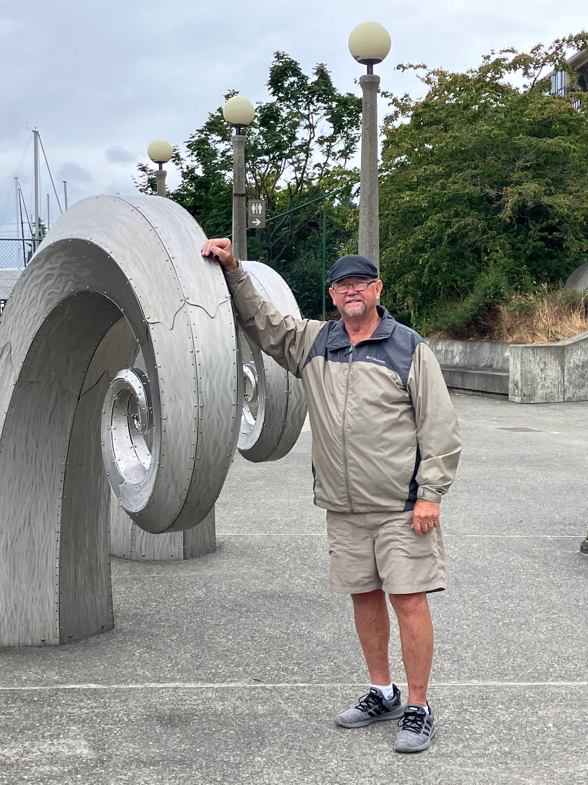 A man is standing in front of a large concrete sculpture.