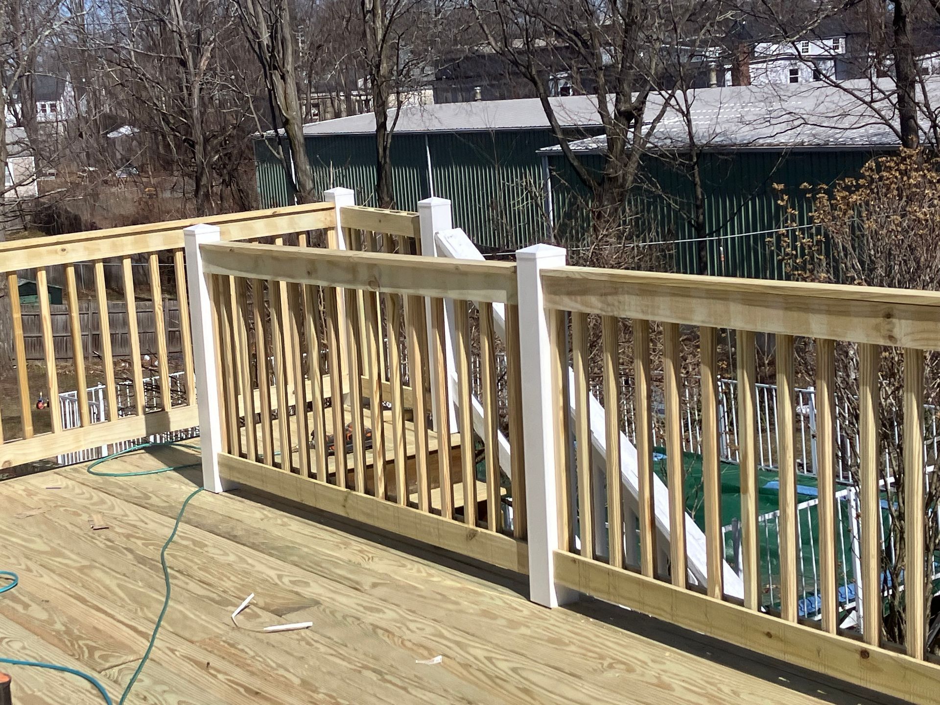 A wooden deck with a white railing and a hose attached to it