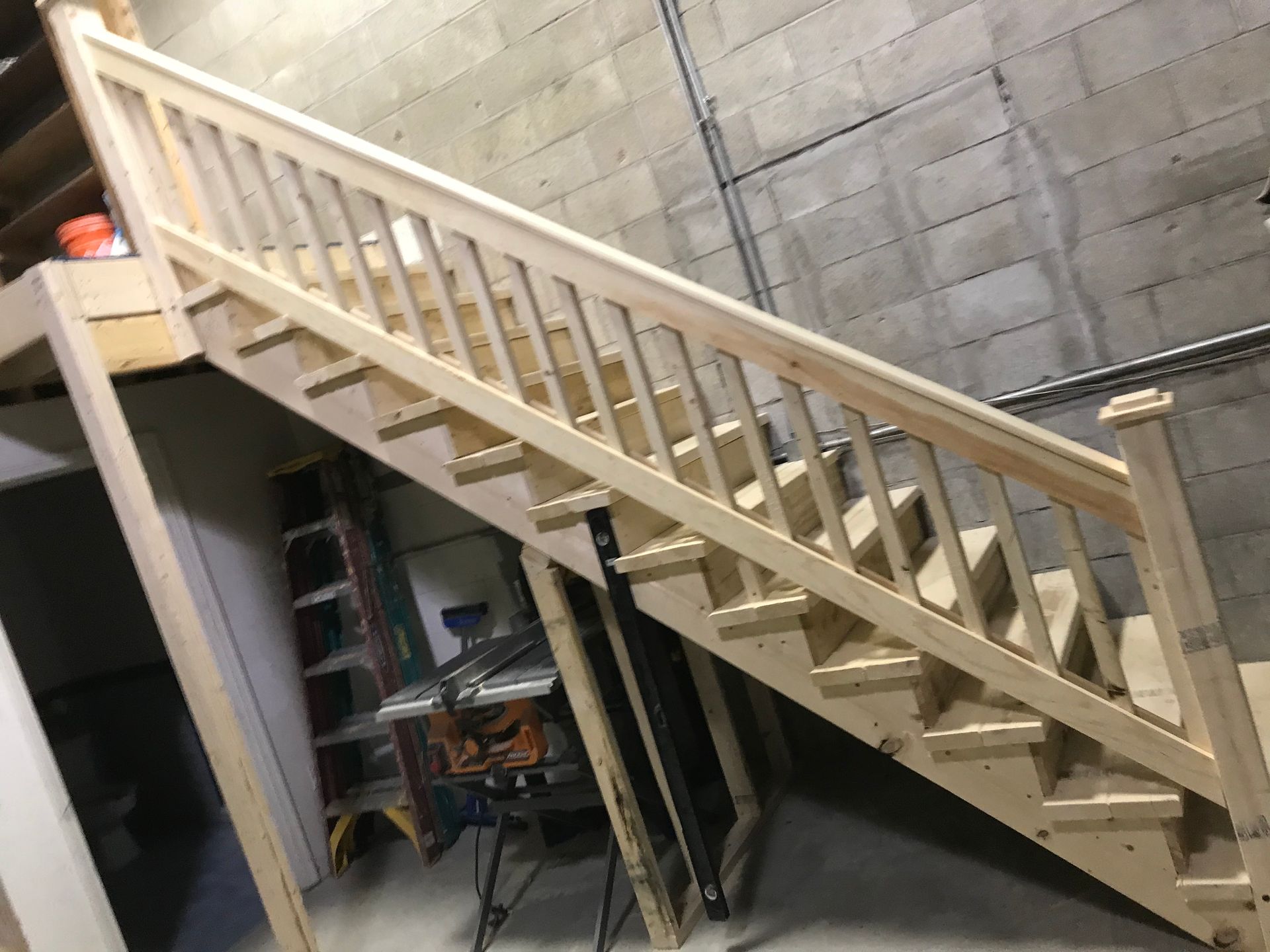 A wooden staircase is being built in a room with a brick wall.