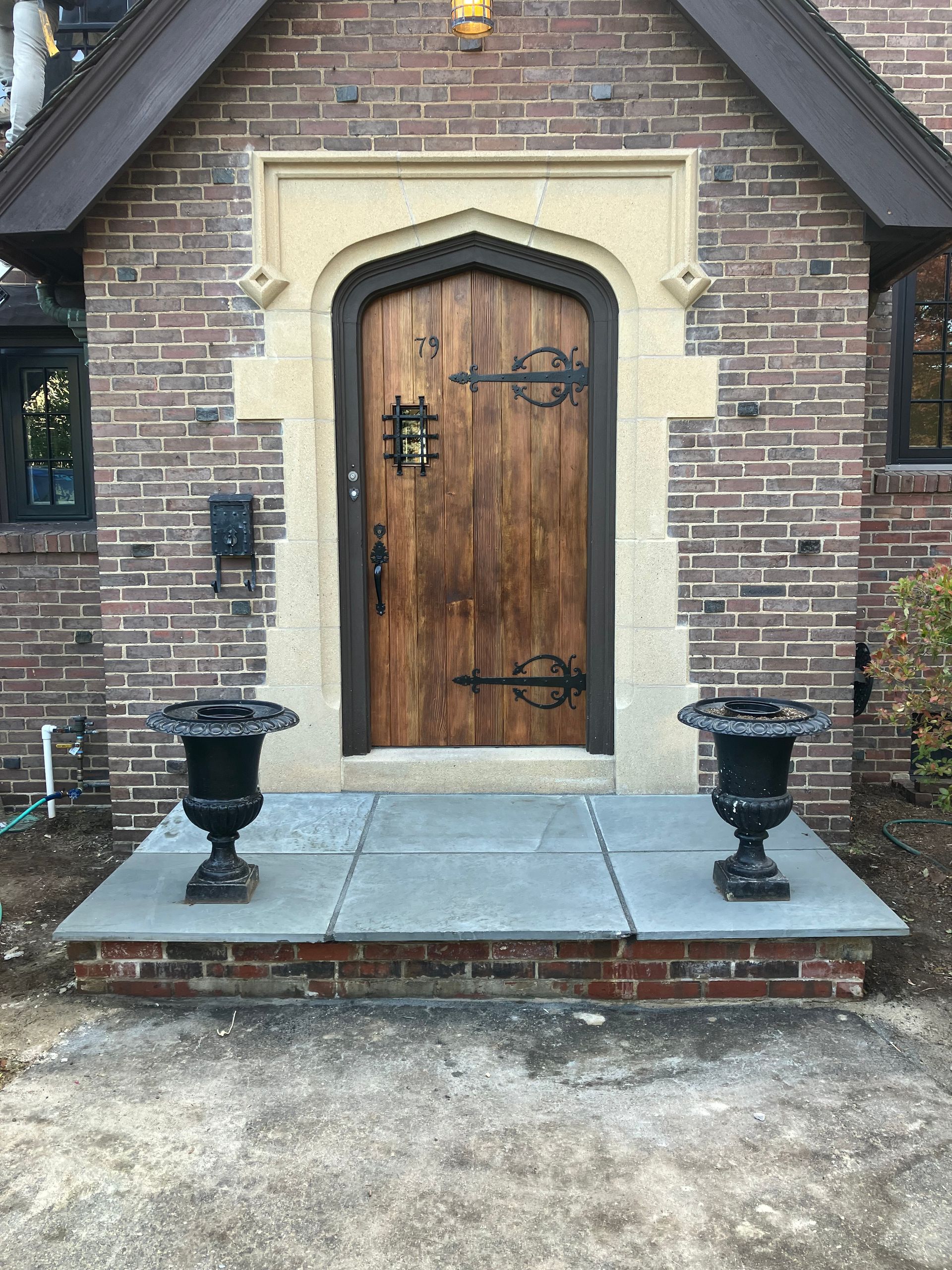 A brick building with a wooden door and two vases in front of it