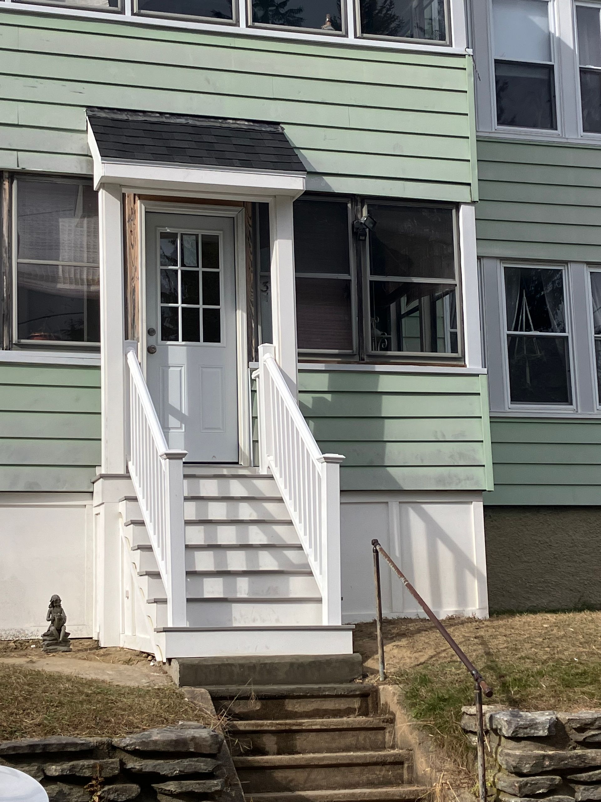 A green house with white stairs leading up to the front door