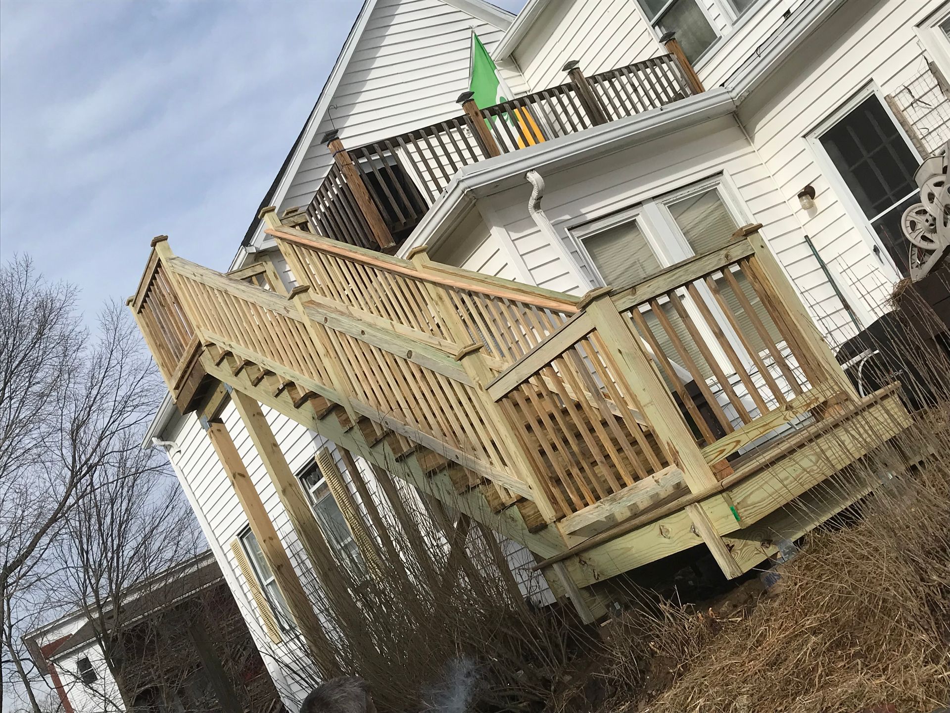 A wooden deck with stairs is in front of a white house.