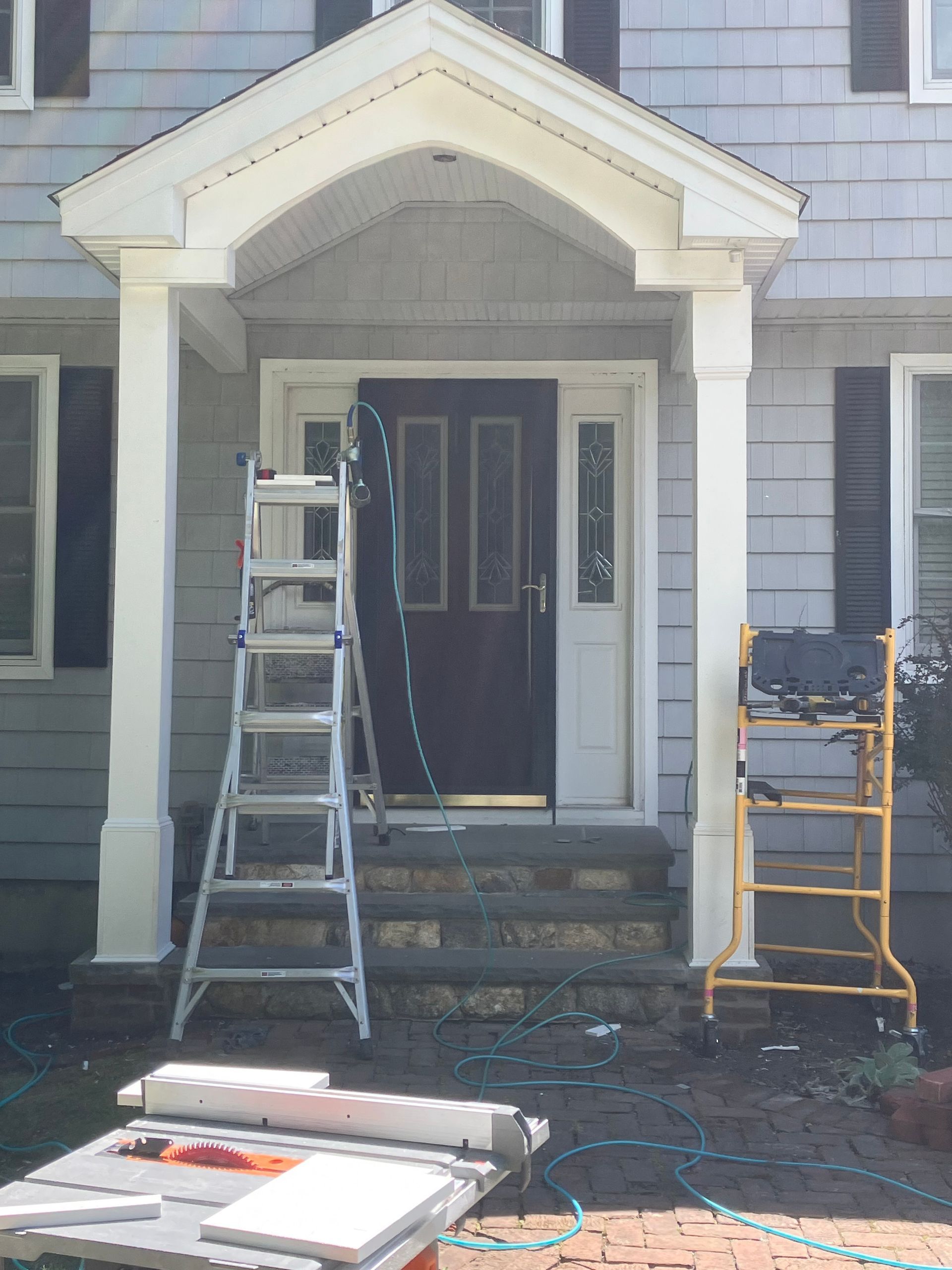 A house with a porch and a ladder in front of it