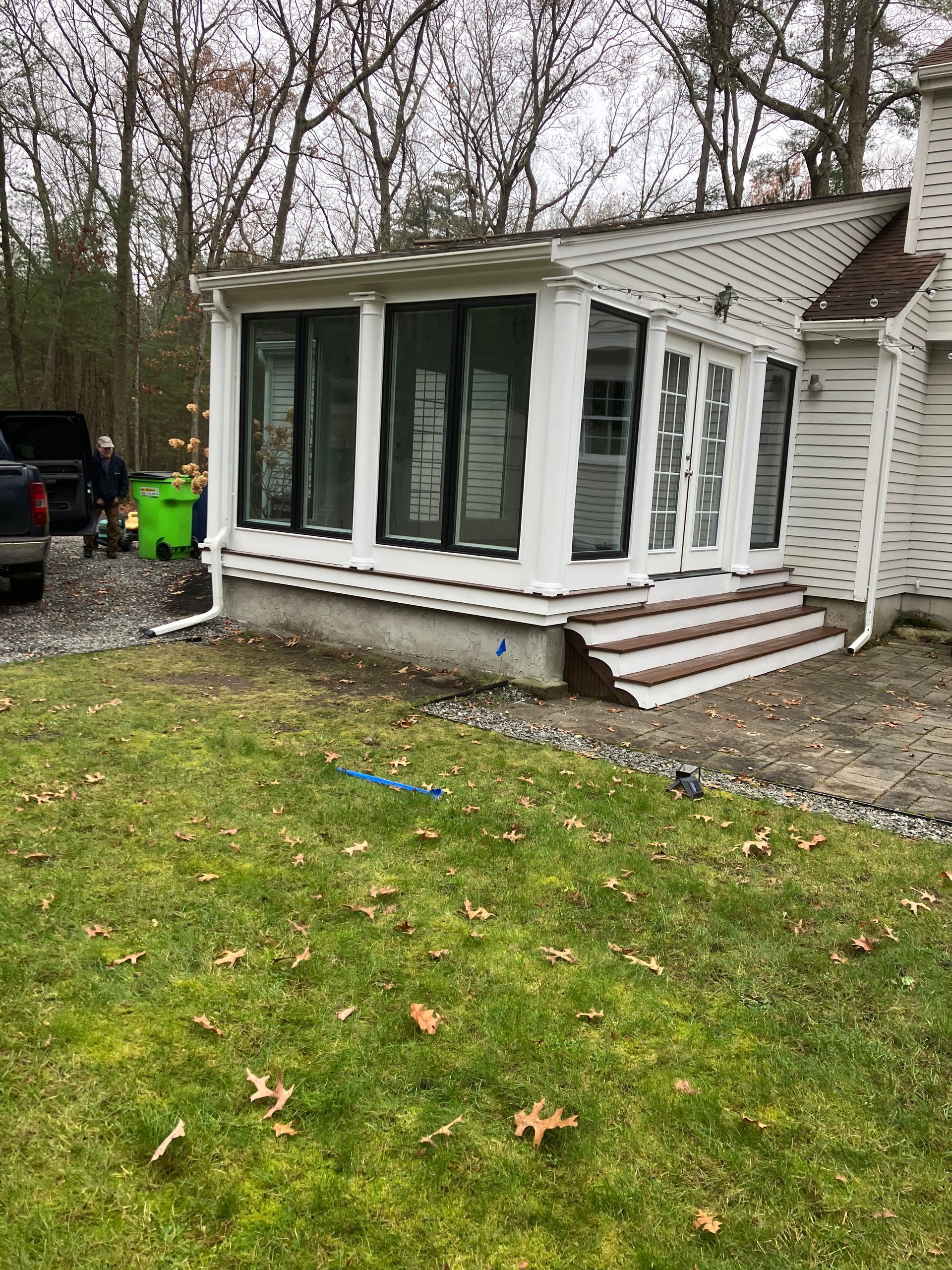 A white house with a porch and stairs is sitting on top of a lush green lawn.