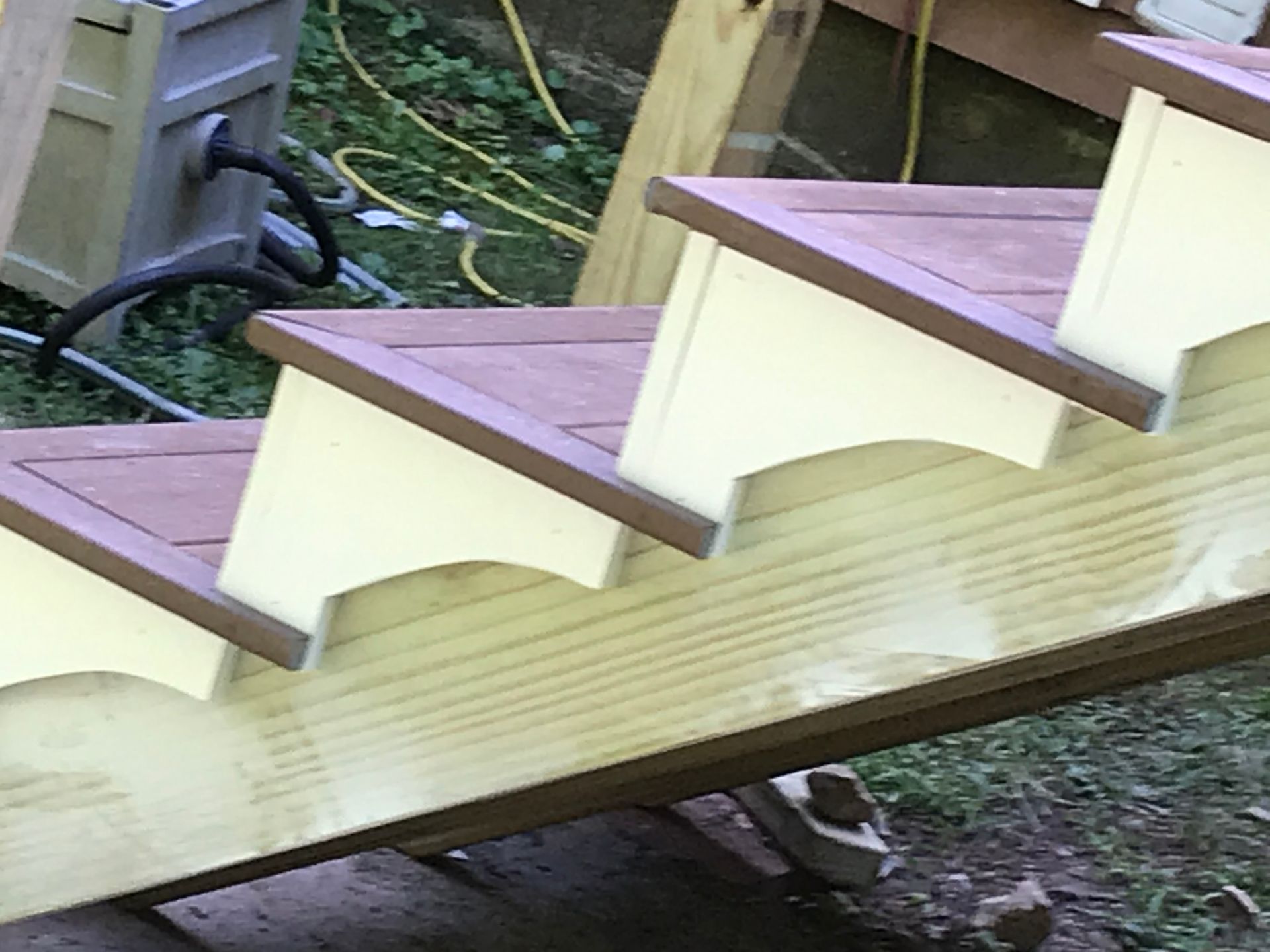 A close up of a wooden staircase with a hose in the background