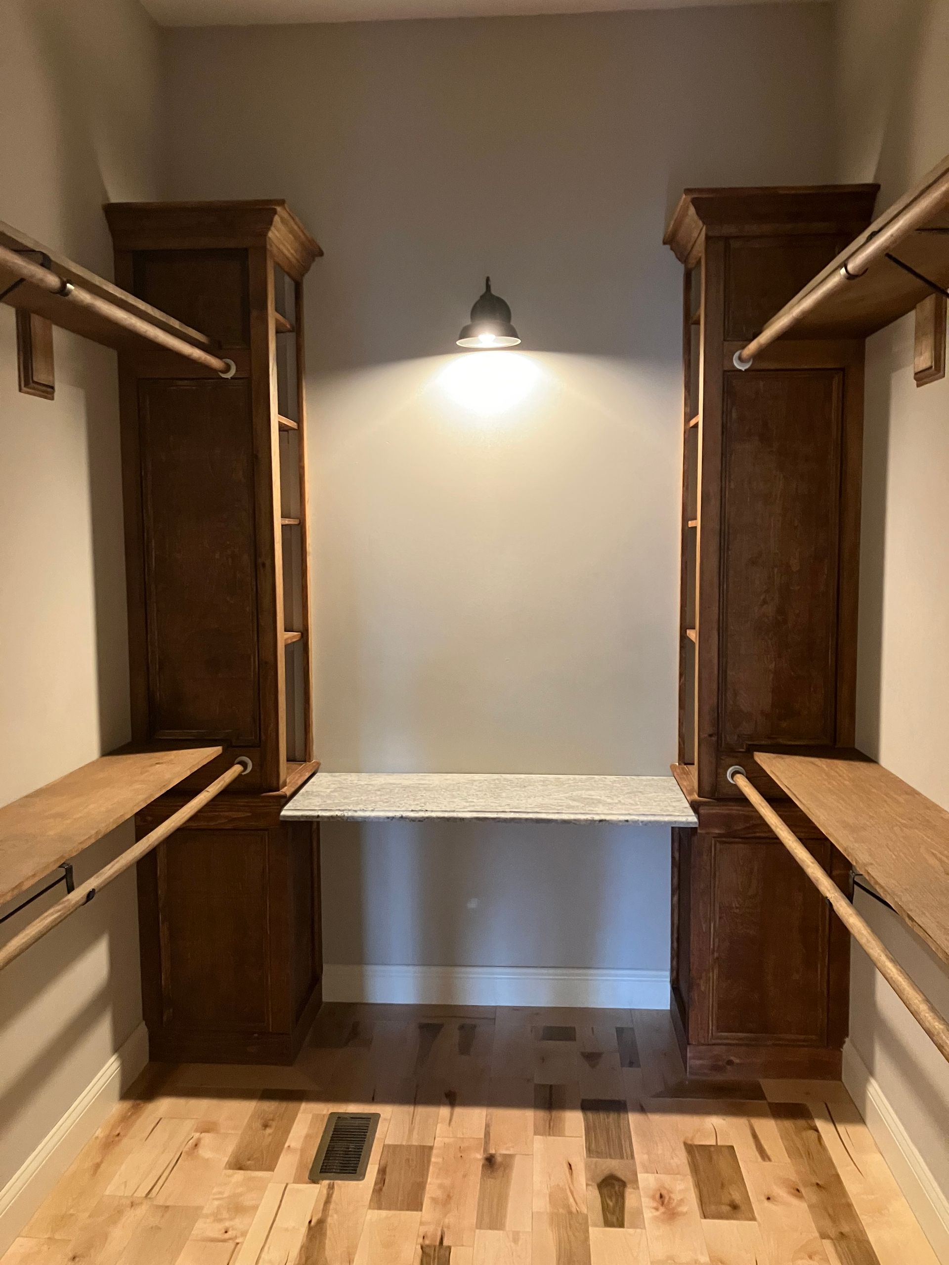 A walk in closet with wooden shelves and a desk.