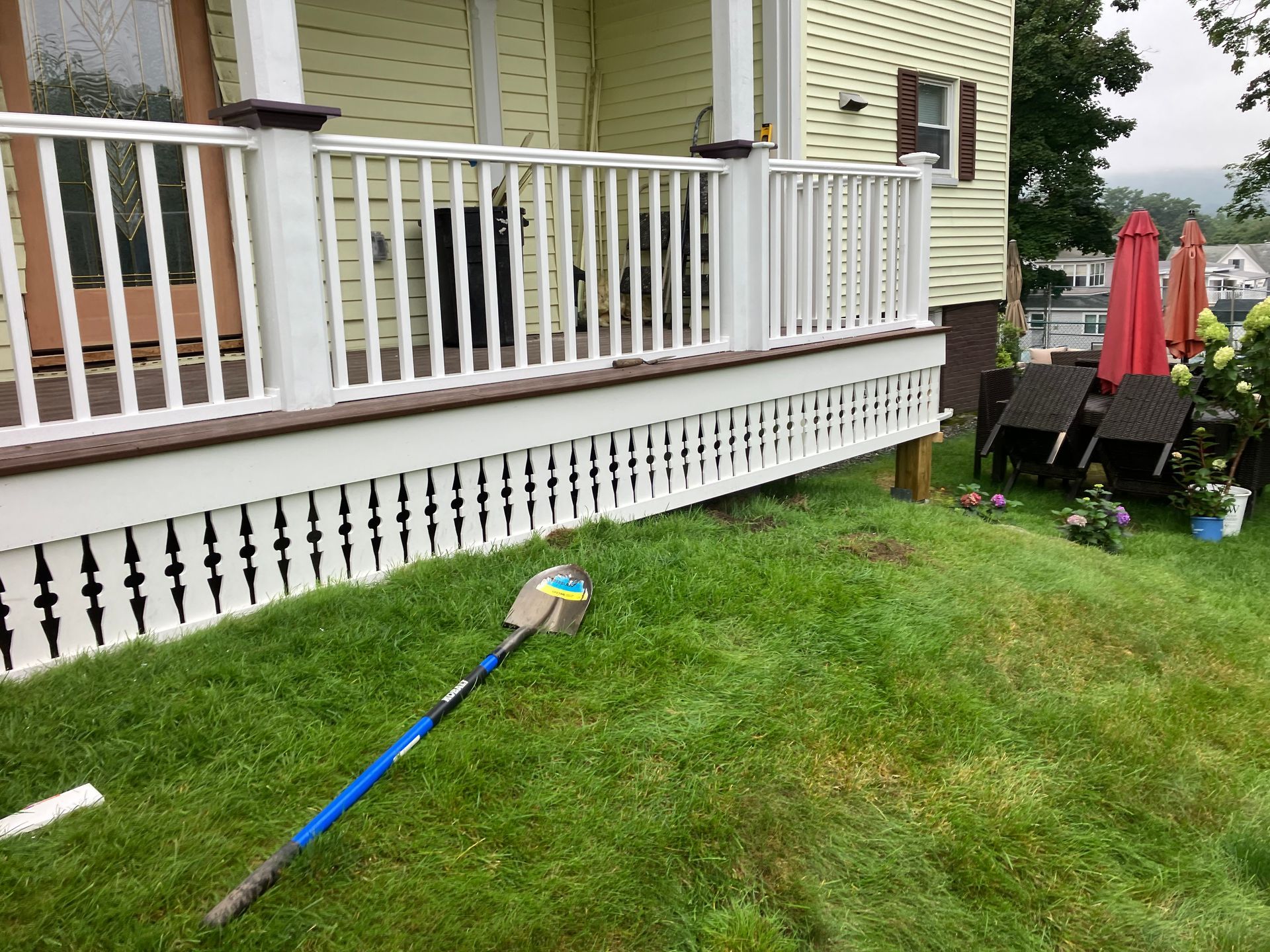 A broom is sitting on the grass in front of a house.