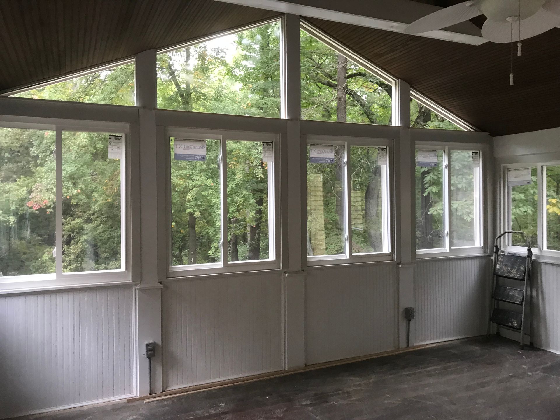 A room with a lot of windows and a ceiling fan