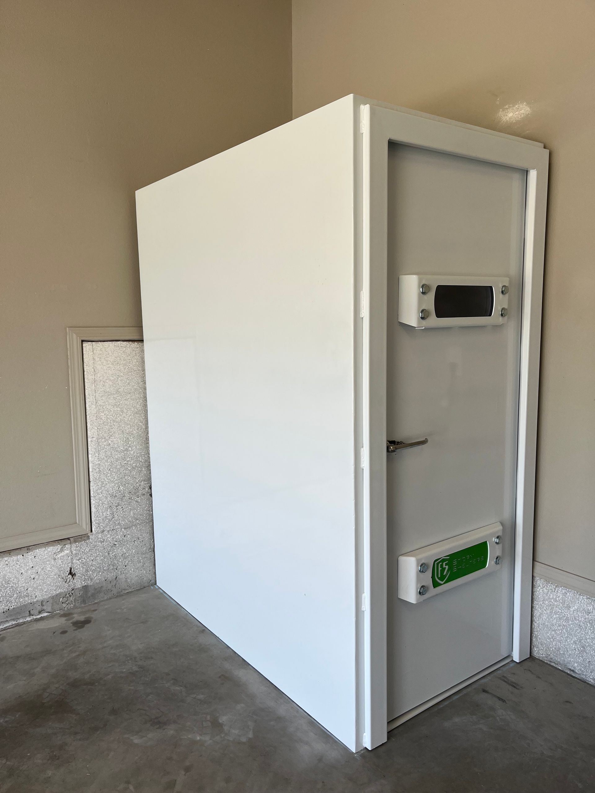 White utility cabinet or enclosed unit with open door and mounted devices, in a concrete garage or utility room