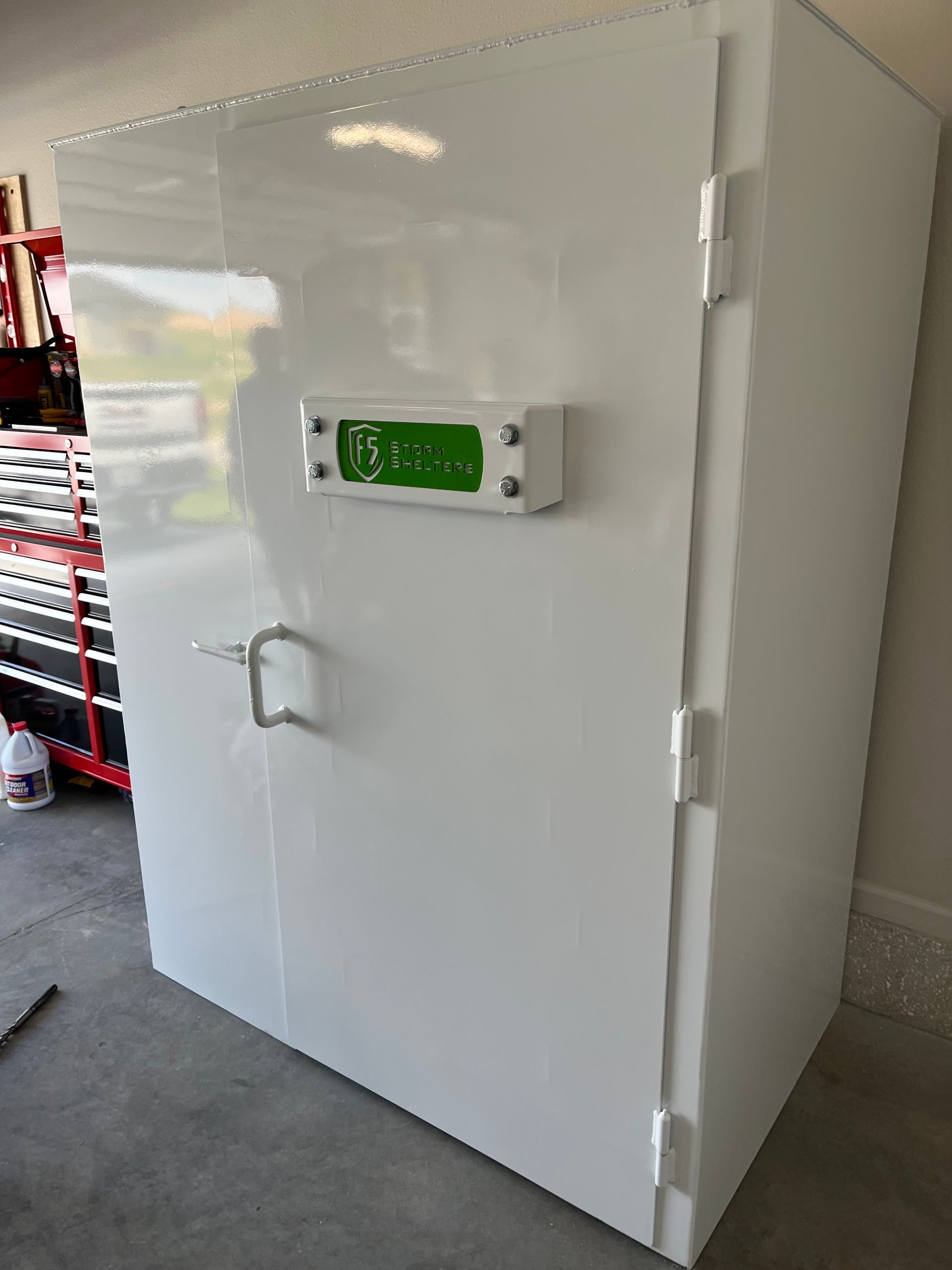 White walk-in freezer door with green digital control panel in a garage-like room