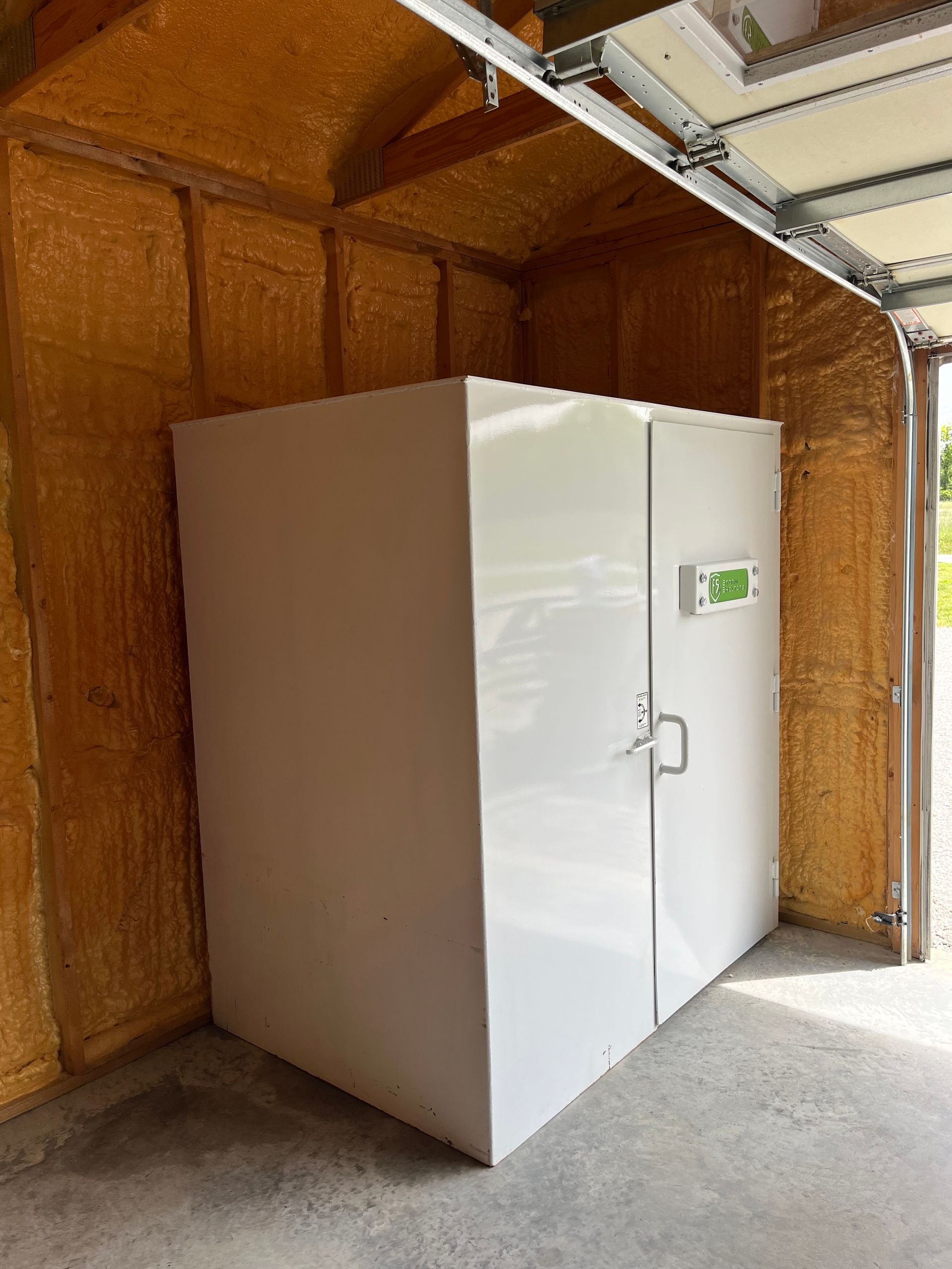 White walk-in freezer in a garage with a small control panel on the door