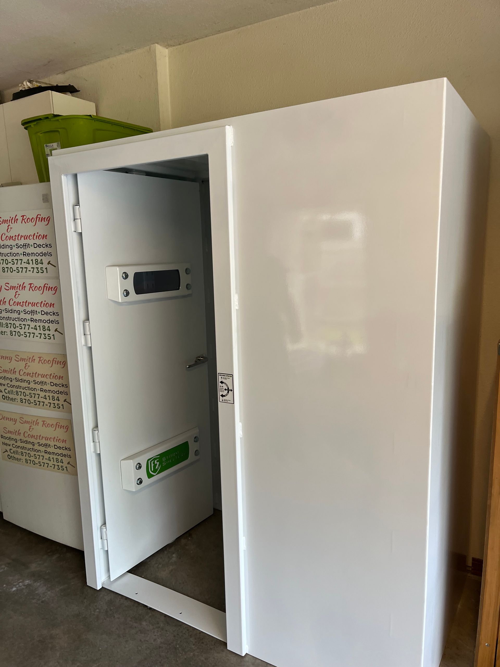 Open white utility cabinet with electrical equipment inside, in a hallway.