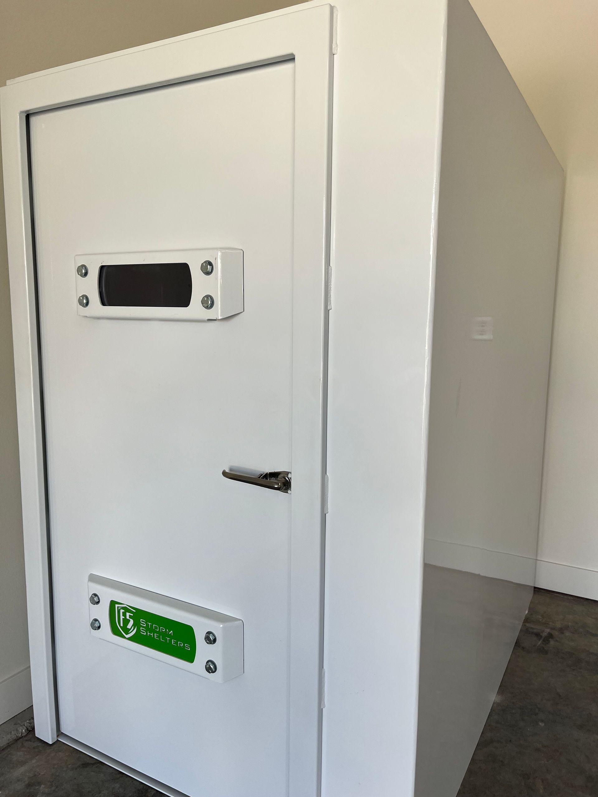 White metal locker-like cabinet with a handle and small display panels in a plain room