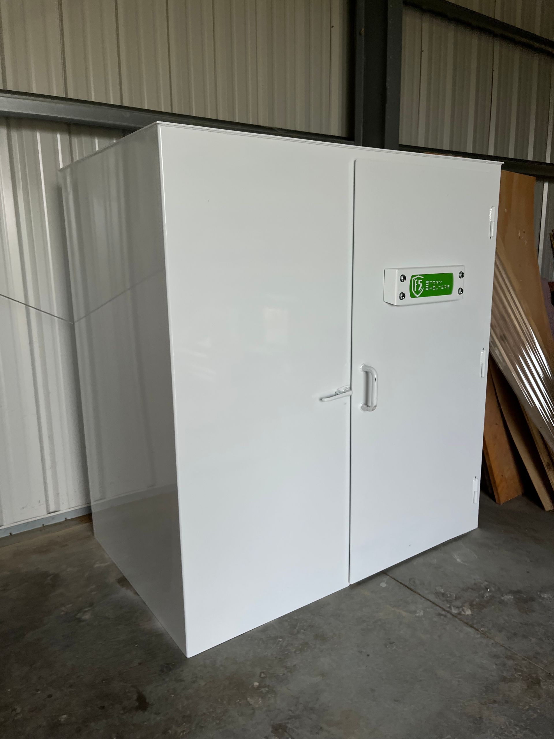 White walk-in industrial chamber with a small green control panel in a warehouse.