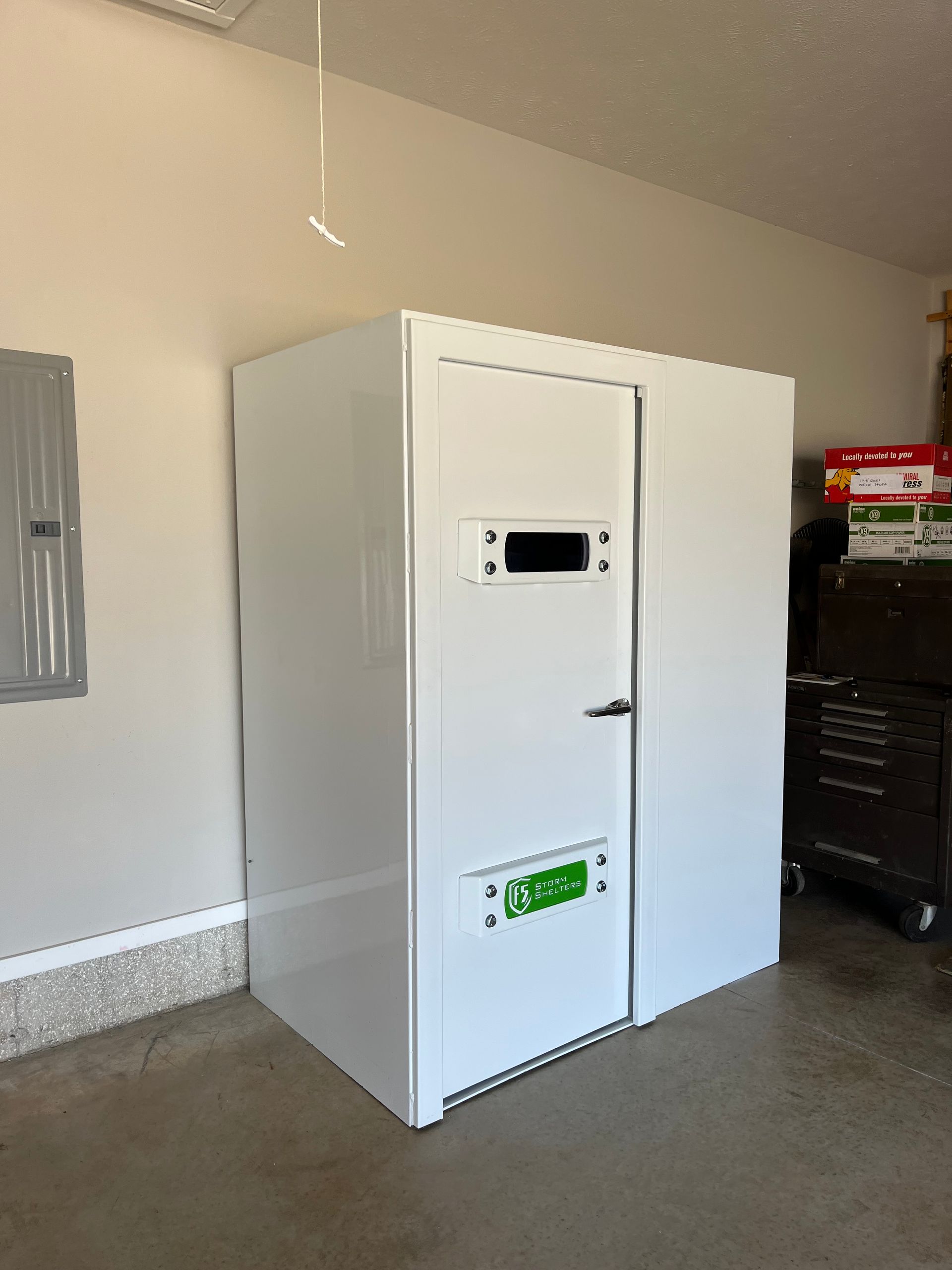 White metal cabinet in a garage or utility room beside a gray wall and tool chest