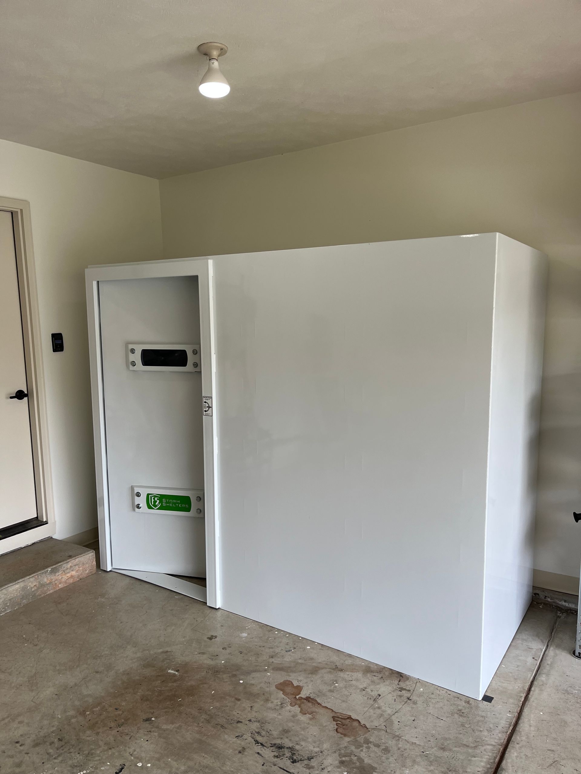 Large white storage unit in an unfinished room with concrete floor and a ceiling light.