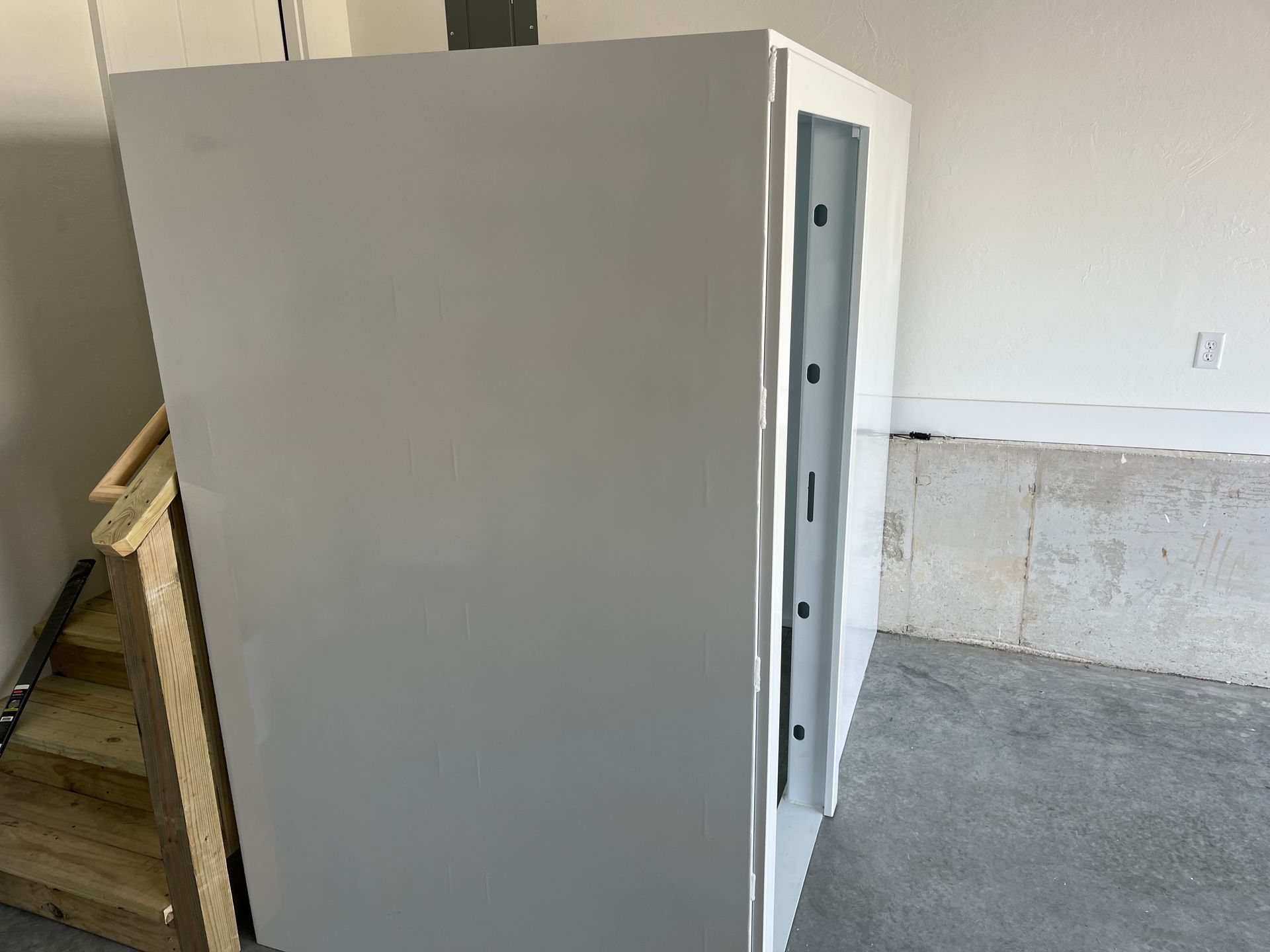 Gray utility cabinet in a garage or workshop, with a side panel and concrete floor visible.
