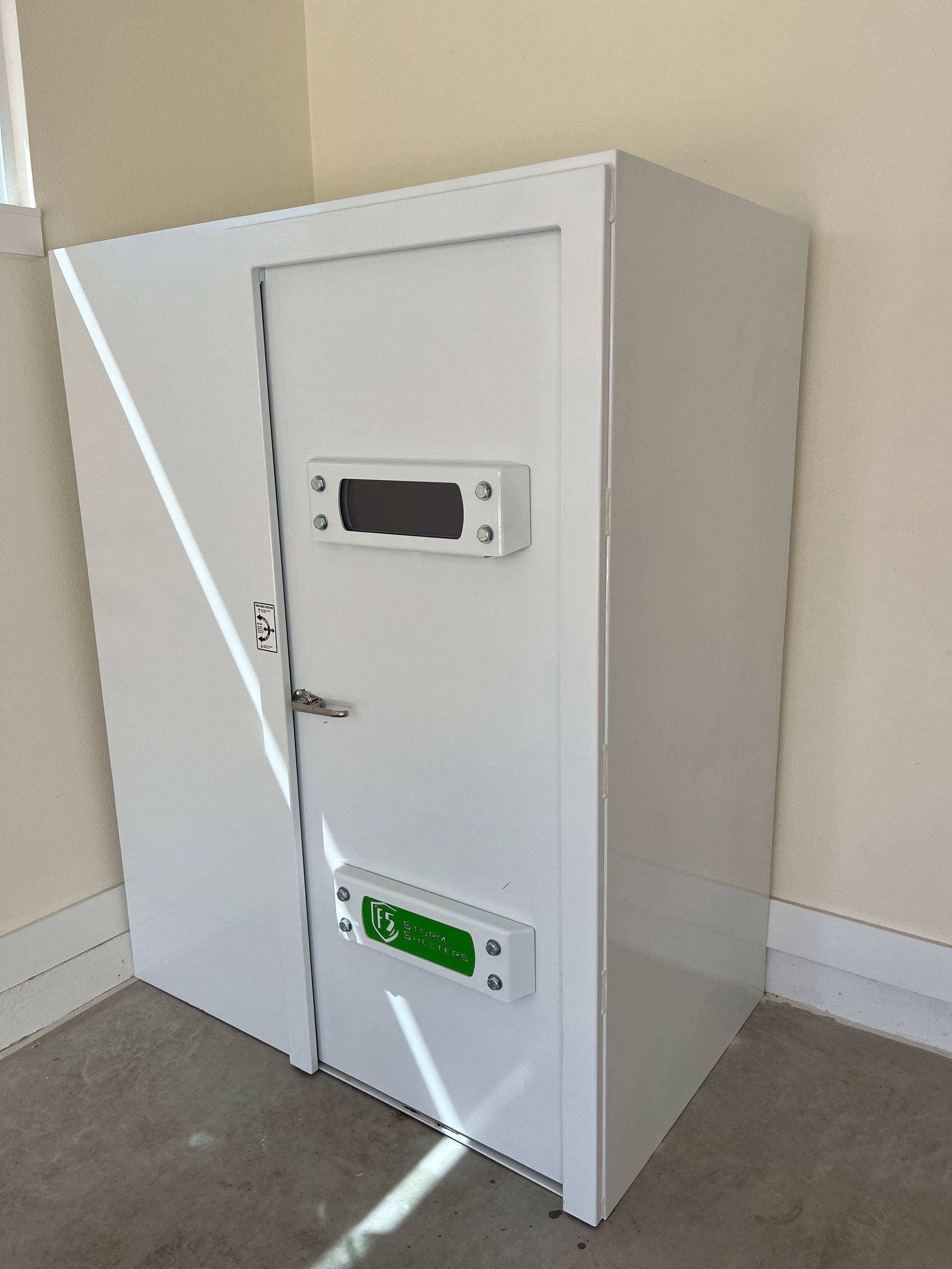 White wall-mounted metal cabinet with two small access doors and vents in a room corner