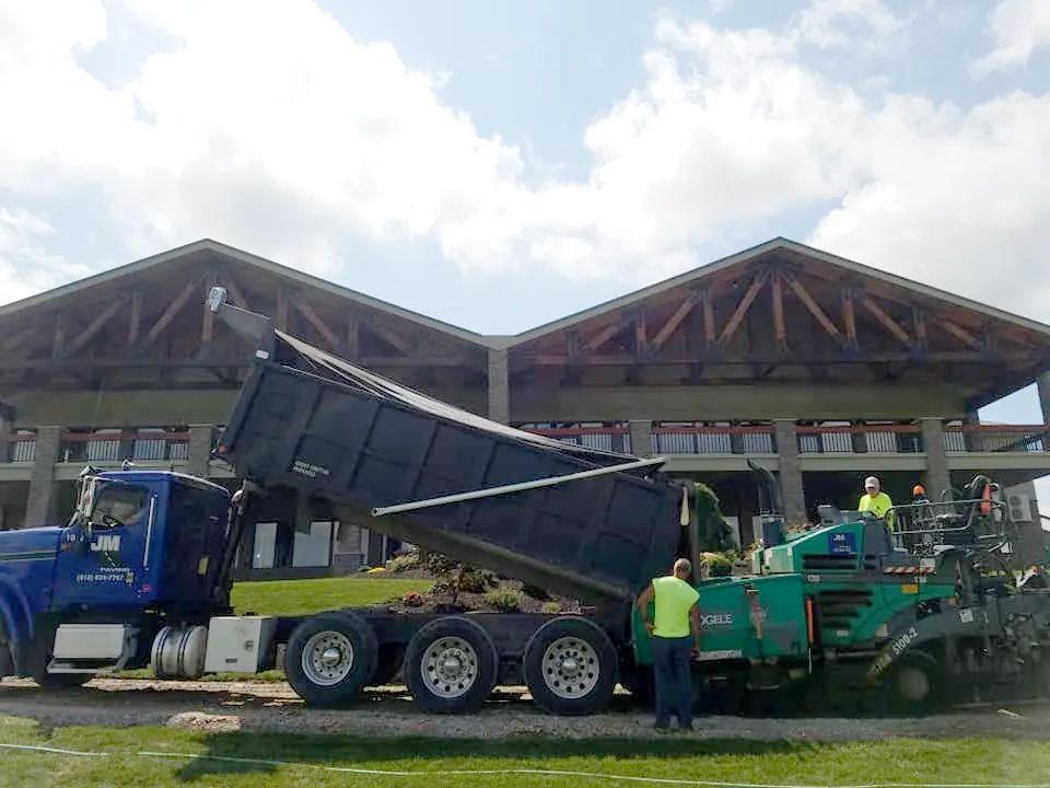 A dump truck is being loaded with dirt in front of a building
