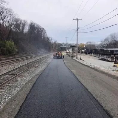 A road is being paved next to train tracks.