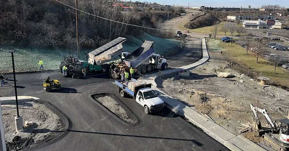 A group of construction trucks are driving down a road.