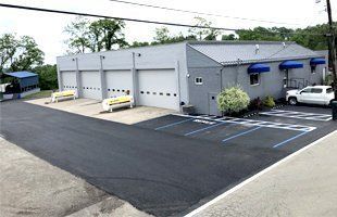 A building with a lot of garage doors and a parking lot in front of it.