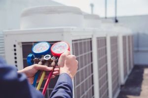 Technician checking HVAC refrigerant gauges on rooftop air conditioning units