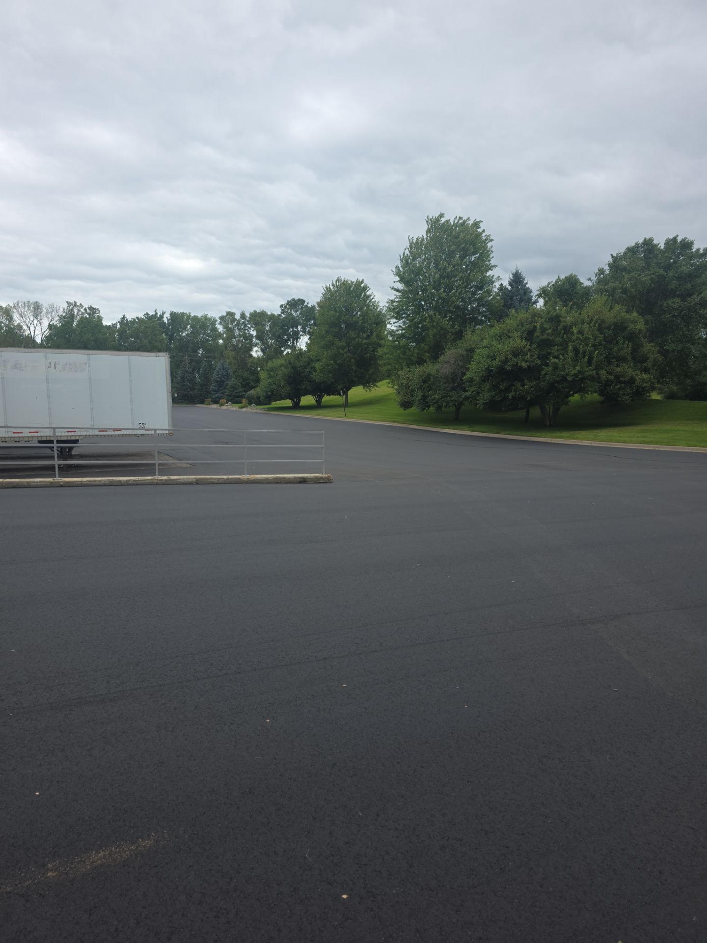 Empty parking lot beside trees under a cloudy sky